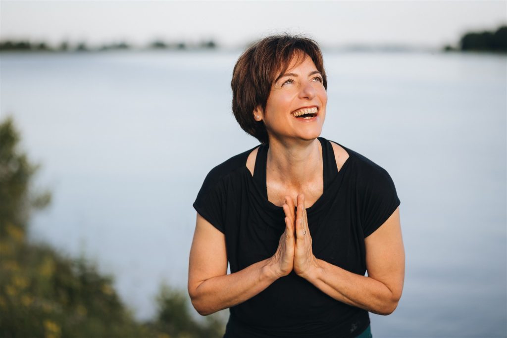 Silvia Nagler an Donau in Gebetshaltung lachend
