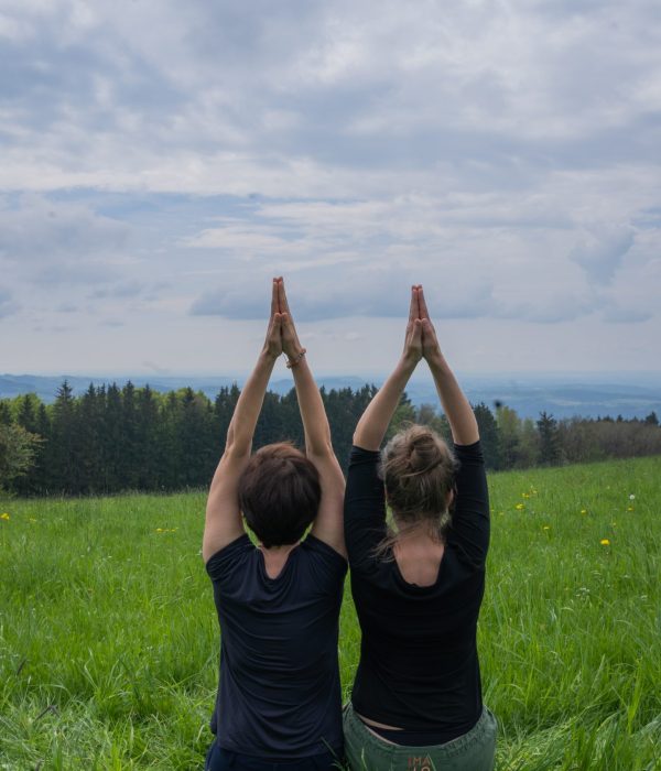 Silvia Nagler und Judith Baumgarten auf Wiese, Ansicht Rücken, Hände zum Himmel